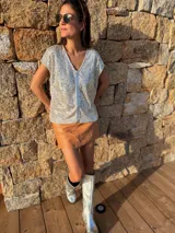Remera de lentejuelas plateadas con forma holgada y favorecedora. En el centro contiene una tira de cuero ovino italiano a tono. Combina con prendas de cuero.