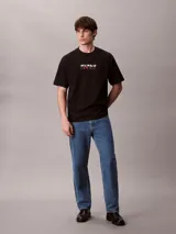 Remera Calvin Klein negra de corte relajado, manga corta y cuello redondo. Presenta un gráfico abstracto estampado en bloques con el logo de la marca en el pecho.