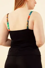 Musculosa tankini negra con estampado de hojas y frutas tropicales, escote con nudo y breteles regulables.