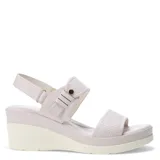 Sandalias de plataforma con diseño de tiras en cuero sintético color tostado. La tira delantera presenta una textura grabada, mientras que la tira trasera incluye un cierre con hebilla y detalle metálico. Posee una base de plataforma blanca con diseño estriado.
