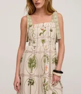 Vestido midi evasé de viscolino, color beige con estampa de flores y follajes en tonos verdes y marrones. Cuenta con escote cuadrado, breteles anchos con lazos estampados y espalda con lastex.