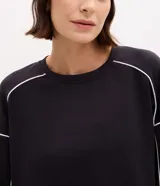 Buzo deportivo de corte oversized en color azul, con cuello redondo, manga larga y puños ajustados. Presenta detalles de frisos contrastantes en color blanco que recorren las mangas y el cuerpo de la prenda.