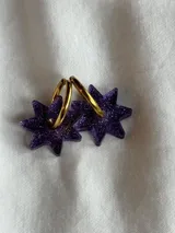 Aros tipo argolla dorada con dije colgante en forma de estrella de acrílico color rosa.