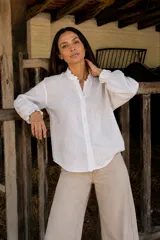Camisa de lino color blanco, con cuello mao con volados, cierre frontal de botones y mangas largas abullonadas con puños elásticos con volados.
