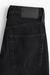 Jean de tiro alto con diseño de cinco bolsillos y perneras amplias de corte recto, confeccionado en denim negro rígido.