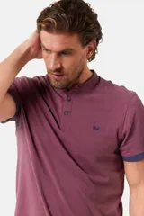 Remera blanca de manga corta con cuello mao y cierre frontal parcial con botones. Presenta detalles en color gris azulado en el cuello y en los bordes de las mangas.