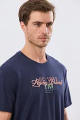 Remera azul marino de manga corta con cuello redondo, confeccionada en mezcla de algodón y poliéster. Presenta un diseño en el frente que combina estampa y bordado con la leyenda "Legacy Brand 1972" en tonos rosado, verde y marrón.