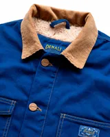 Campera estilo workwear de Denali, confeccionada en canvas resistente color azul royal. Cuenta con interior forrado en corderito sherpa, cuello de pana en color tostado, cierre frontal con botones metálicos color cobre y cuatro bolsillos frontales.
