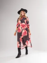 Vestido camisero largo con estampado floral en tonos rojos y negros, con cuello camisero, abotonadura frontal y mangas largas con puños abotonados.