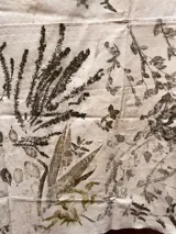Mantel rectangular de algodón color crudo con estampado botánico en tonos marrones y verdes.