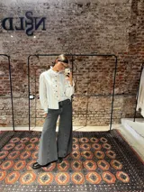 Camisa de corte clásico con estampado de rayas verticales en tonos celestes y marrones. Presenta volados delicados en el frente y en el cuello, cierre frontal con botones y mangas largas con puños ajustados.