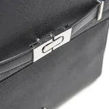 Mochila de diseño estructurado en color negro, confeccionada en material símil cuero con textura granulada. Presenta una solapa frontal con cierre metálico decorativo y logo de la marca en la parte inferior.