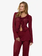 Blusa de manga larga con escote en V, volados frontales y tejido calado semi-transparente, confeccionada en punto liviano de fit ajustado.