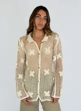 Camisa beige de crochet con diseño de flores, cuello clásico y cierre con botones.