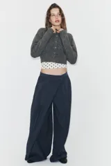 Pantalón de tiro alto con diseño cruzado tipo pareo en el frente, pernera ancha y caída fluida.