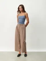 Pantalón de vestir color tostado de corte ancho y relajado, tiro alto con trabillas para cinturón, pinzas frontales y bolsillos laterales.