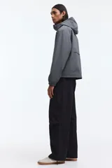 Campera rompevientos de nylon repelente al agua, con capucha ajustable, cierre frontal completo, bolsillos laterales y puños elásticos.