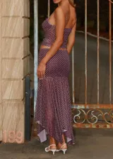 Conjunto de dos piezas compuesto por un top de tirantes finos con escote recto y fruncido, y una falda midi de corte sirena con bajo asimétrico. Ambas prendas presentan un estampado de lunares blancos sobre fondo violeta oscuro.