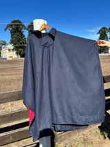 Poncho de paño de lana doble, color azul marino en el exterior y rojo en el interior, con cuello y detalle de bolsillo con solapa y botón.