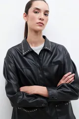 Sobrecamisa negra de cuero sintético con cuello camisero y tachas plateadas.