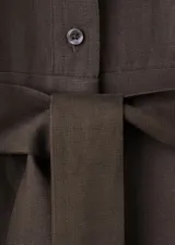 Mono largo de lino y lyocell en color marrón, con diseño recto, cuello camisero, manga corta, bolsillos laterales y cierre delantero con botones. Incluye un cinturón ajustable del mismo tejido con hebilla metálica.