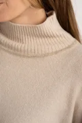 Sweater tipo polera de calce oversize, con diseño color block que combina tonos beige y marrón. Presenta cuello alto, mangas largas con puños acanalados y un panel inferior acanalado a juego.
