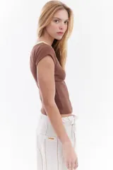 Top de canalé amarillo con cuello redondo y ribetes en color bordo, mangas cortas y detalle de logo bordado en el pecho.