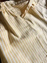 Short de lino a rayas blancas y amarillas, con cintura elastizada y lazo ajustable en el frente.