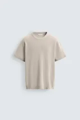 Camiseta de punto de algodón con textura perlada, corte regular fit, cuello redondo y manga corta con terminaciones en rib.