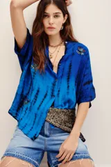 Camisa de viscosa con estampado tie-dye en tonos de azul y negro, de manga corta, cierre frontal con botones y bordados decorativos en el frente.