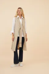 Chaleco largo color marrón claro, abierto, con lazo en la delantera y bolsillos ojal. Confeccionado en lana fina sin teñir.