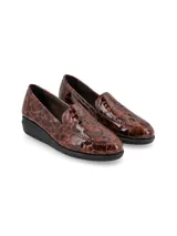Zapato tipo mocasín slip-on con acabado en cuero charol texturizado con efecto reptil en tonos marrones. Presenta una suela de plataforma plana de color negro con diseño dentado y una estructura anatómica para mayor confort.