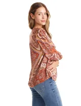 Blusa de gasa estampada con diseño de arabescos en tonos tierra. Presenta cuello a la base con escote en V, hombros con detalle de punto smock y mangas 3/4 con puños anchos también en punto smock.