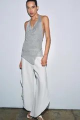 Top halter de punto con hilo metalizado, color plateado, con escote pronunciado y tirantes para anudar al cuello.