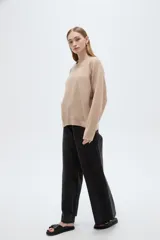 Sweater holgado de punto color beige con cuello redondo a la base y mangas largas raglán.