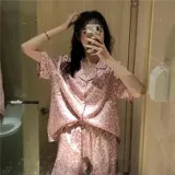 Pijama de dos piezas compuesto por una camisa de manga corta con botones frontales y un short, ambos con estampado animal print y detalles de vivo en contraste.