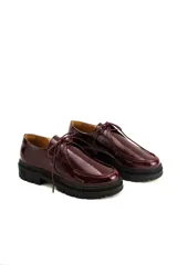 Zapatos tipo wallabee de cuero charolado color bordó, con cordones al tono y suela track de goma negra con plataforma.
