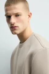 Sudadera de manga corta con corte relajado, confeccionada en tejido técnico compacto de algodón con elasticidad. Presenta cuello redondo y detalle de tacha metálica en la espalda.