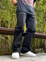 Pantalón negro de gabardina, corte ancho tipo carpenter, con costuras blancas contrastantes.