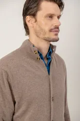 Sweater de lana lambswool color gris, con cuello alto, cierre frontal de botones y dos bolsillos delanteros tipo parche.