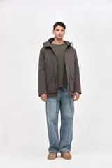 Campera tipo parka de gabardina color beige, con capucha ajustable, cierre frontal y bolsillos laterales con solapa. Presenta un diseño clásico con interior capitoneado.