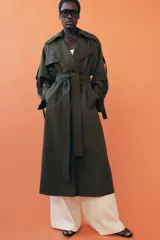 Trench oversize de Zara Woman Collection, color verde militar, con cuello solapa, cierre frontal cruzado con botones y cinturón ajustable del mismo tejido. Presenta mangas largas con trabillas ajustables y bolsillos delanteros.
