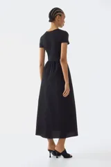 Vestido maxi negro con cuerpo entallado de punto interlock, escote redondo, mangas cortas, costura fruncida en la cintura y falda larga con volumen.