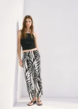 Pantalón fluido de corte recto con estampado tropical y cintura elástica, confeccionado en mezcla de viscosa y poliamida. Cuenta con bolsillos laterales.