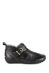 Botita baja clásica de cuero vacuno liso en color negro, con interior de corderito. Presenta una tira lateral con hebilla metálica dorada y elástico para mayor ajuste, costuras pespunteadas decorativas y una tira trasera para facilitar el calce.