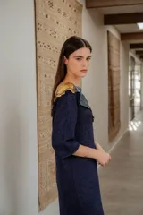 Vestido largo azul con cuello con apliques de cuero y flecos en el ruedo.