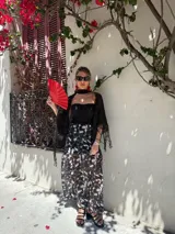 Falda larga de tela estampada con flores y hojas en tonos marrones, negros y violetas. Tiene elástico en la cintura.