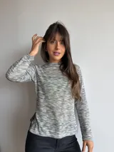 Remera básica de manga larga y cuello redondo, confeccionada en tejido melange en tonos grises y blancos con sutiles destellos multicolores. Presenta un corte recto con aberturas laterales en el dobladillo.