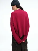 Sweater de tejido de punto color beige, con cuello redondo, hombros caídos y costura central vertical en el frente. Presenta un diseño de corte relajado, con largo asimétrico y aberturas laterales en el ruedo.