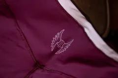 Calza deportiva corta color bordó con tiro alto y costuras planas. Presenta un logo estampado en blanco en la pierna, que consiste en un objeto con alas.